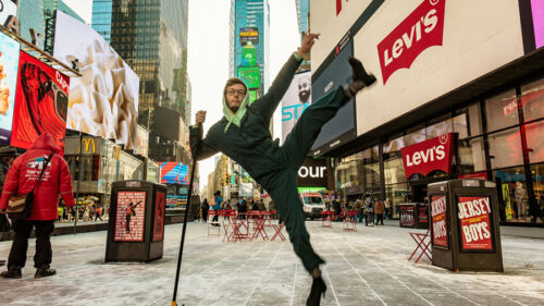 A performer holding a broom and dancing in Times Square